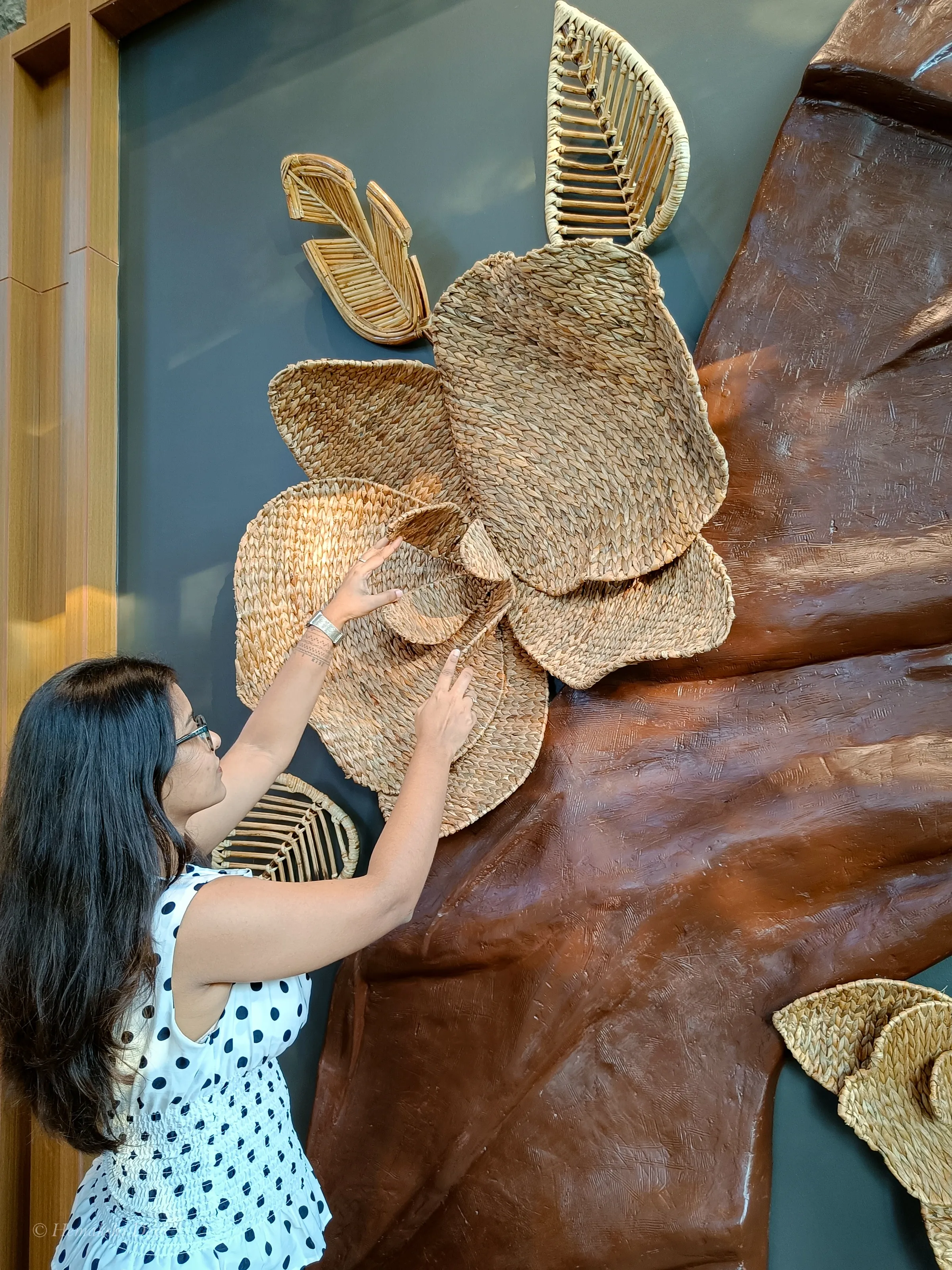 Hemakshi Devi hand-finishing the cane orchid sculpture within the reception fibre installation